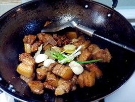 12、虎皮鹌鹑蛋红烧肉,倒入料酒、生抽、老抽，把准备好的葱姜蒜等香料一起放进去继续翻炒