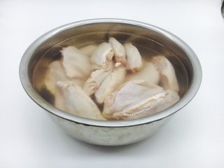 1、鸡翅焖土豆,在新鲜的鸡翅背部划两刀，放在清水里浸泡30分钟，挤一挤血水，洗干净备用。