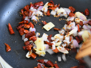 9、川菜"辣子鸡丁"学会了技巧,又香又下饭,炒香后倒入8g蒜片、5g姜片、15g洋葱粒,炒匀