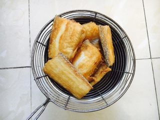 6、红烧带鱼,煎好的鱼放在笊篱里沥油。