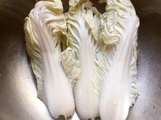 2、醋溜白菜,将白菜一片一片掰下来放洗菜盆里,在水龙头下冲洗干净。