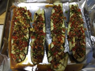 8、蒜香烤茄子,蒸好的茄子放在铺了锡箔纸的烤盘上，把准备好的佐料均匀铺在茄子上，往茄子的网格缝里塞一些佐料，把剩余料汁浇在茄子上