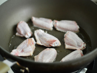 2、啤酒鸡翅,锅里倒入少许油，将鸡翅皮那面朝下放入煎制