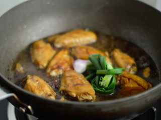 7、啤酒鸡翅,放入葱结，盖上盖子转小火焖煮约20分钟