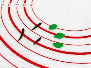 12、吉祥如意小猪馒头,黑色小面团做成橘子的蒂,绿色面团做出小叶子的造型,用水果刀压按出叶子的纹路。