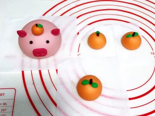13、吉祥如意小猪馒头,把橘子蒂插入孔中,绿色的叶子也粘上,然后取一点点搓圆做小猪的眼睛。