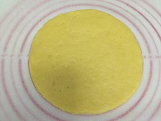 8、红豆葡萄干松饼,将面团分成两份，放一张油纸，取一份面团在油纸上擀成圆形的饼状。