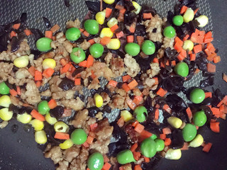 7、超级好吃的饺子皮烧麦,依次加入豌豆粒，玉米粒、胡萝卜粒、木耳，继续翻炒。