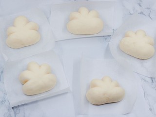 3、云朵馒头,取一颗馒头面团，稍微压扁，手掌顶住一边，用刮刀沿面团压出四条线，中间两条线间隔略宽一些，这样就能够形成云朵状，其他的面团手法一样