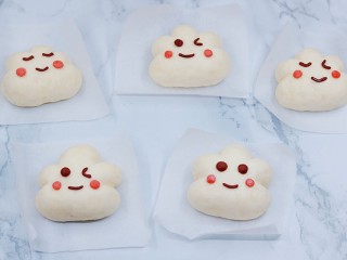 8、云朵馒头,取比眼睛稍小的粉红色面团，搓成圆粒，做成腮红。放在脸蛋的位置，稍微压平。制作完成三种表情的云朵馒头