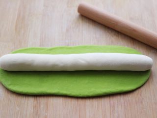 12、翡翠白玉生煎包,把其中一个绿色的面团擀成长方形薄片，把另一个白色面团放在上面。
