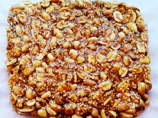 11、美味花生糖,倒在铺有油纸的案板上，用木铲压平