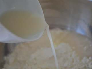 4、玫瑰花馒头,将酵母水慢慢倒入面粉中。 注意：因面粉吸水性不同，导致水量不同，所以不要一次性倒入所有水，要一点点加水，边加边搅拌。 