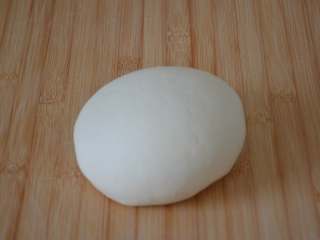 7、玫瑰花馒头,面板上撒少量干面粉，将面团反复揉搓排气到位，这个过程即俗称的揣面。此时的面团约460克左右。