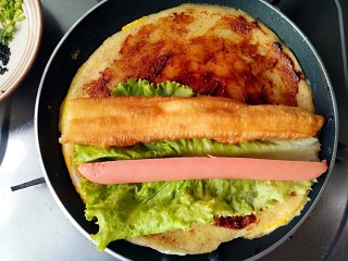 9、杂粮煎饼,放入油条（薄脆果篦儿），生菜和火腿肠。我家的天津老佛爷说：“在煎饼果子里放生菜和火腿肠的都是邪教，正宗的天津煎饼果子只放油条或果篦儿。”我说：“这是我大山东的改良版，这才叫营养又接地气！哈哈哈！”