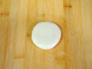 25、经典版蛋黄酥,反过来，收口朝上放，先用手掌轻轻按扁。这个时候能感觉到油皮和油酥软硬度相近的重要性，硬度差不多的话，按扁的时候油酥会在油皮里均匀的铺开。如果油皮很软，油酥比较硬，那就不容易做均匀，同样对最后的起酥效果有影响。