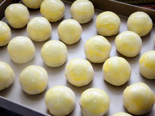 42、经典版蛋黄酥,刷蛋黄液，蛋黄液比全蛋液颜色漂亮，柴鸡蛋蛋黄比品种鸡蛋蛋黄颜色漂亮。刷蛋液也有两种不同的刷法：如果喜欢蛋黄酥外表完整，没有任何裂纹的话，刷完蛋黄液就撒黑芝麻，直接进烤箱开始烘焙。如果喜欢蛋黄酥表面是冰裂感觉的话，就刷两遍蛋液，第一遍刷完后稍微晾干，再刷第二遍，边刷边撒黑芝麻，如果等24个全刷完，黑芝麻可能就粘的不太牢固了。撒完黑芝麻后再稍微晾干再进烤箱。这样烤制的过程中，逐渐膨胀开的酥皮就会把已经凝固的蛋黄液撑开，形成漂亮的冰裂纹。