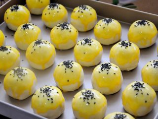 43、经典版蛋黄酥,个人更喜欢冰裂纹，用的是第二种刷蛋液方法。撒黑芝麻的时候，用手指捏着一点黑芝麻，轻轻松开，自然就落到了蛋黄酥表面，这样撒的自然，才会比较好看，不要把整个蛋黄酥都粘的到处都是芝麻，那样就不漂亮了。