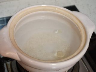 7、皮蛋瘦肉粥,泡好的大米倒掉水重新加入大半锅清水(大约大米量的三倍),滴入一滴色拉油,开中火煮开后换小火慢慢熬煮。中间不时搅拌下,防止米粒糊在锅底。