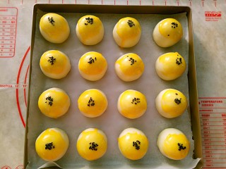 14、蛋黄酥,包好的蛋黄酥收口朝下，整齐地摆放在烤盘里。表面刷上蛋黄液点缀上黑芝麻。