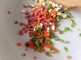 2、洋葱圈煎蛋饼-可以和宝贝抢着吃的美食,热锅，加少许橄榄油，放入青椒、火腿、胡萝卜丁和玉米粒（这一步也可直接省略，直接将食材和淀粉鸡蛋混合）。