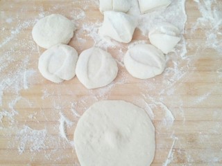 8、早餐生煎包,面团略微排气后分割成等量的剂子,剂子按成扁状,在幹成中间略厚的包子皮。