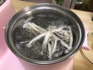3、三鲜菌菇汤,早餐机煮锅加入清水烧开焯水平菇和海鲜菇3分钟捞出沥干。