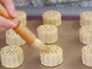 15、蛋黄莲蓉月饼,送入烤箱，180度烤5分钟，把鸡蛋搅打均匀，拿刷子蘸上少许蛋液刷在月饼表面，送回烤箱180度再烤15分钟