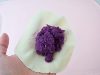 9、饺子皮紫薯饼,用左手托住饼皮,中间放入适量的紫薯泥