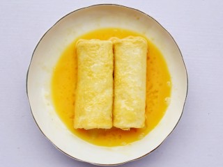 9、爆浆芝士火腿土司卷,卷好的土司卷，放到蛋液中滚一下。