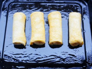 10、爆浆芝士火腿土司卷,放入刷了一层油的烤盘。