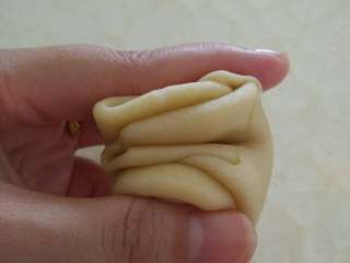 9、蛋黄酥,把卷好两次的面团用手在中间一压，然后对折，用擀面杖擀成中间稍厚四边薄的形状