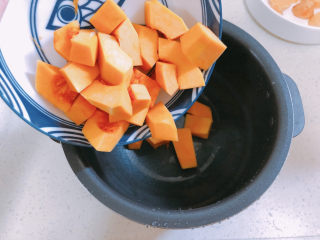 10、红薯南瓜粥,把南瓜块放入电饭煲。