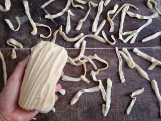 6、时蔬炒刀削面,左手举面团，右手拿削面刀刀，将面一片一片地削到案板上（或者直接削到开水锅中）。