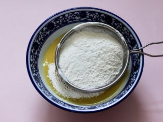 5、酥得掉渣的芝麻桃酥,碗中再筛入称重后的中筋面粉和泡打粉。