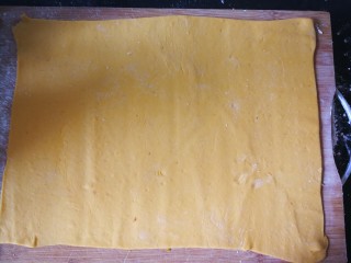 10、千层手撕南瓜馒头,案板上撒上些手粉，将面团擀成规则点的长方形薄片。