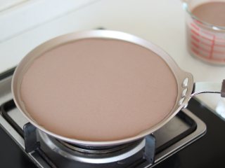 11、巧克力毛巾卷,准备制作饼皮，首先需要准备湿抹布，用于冷却锅底。之后平底锅倒入面糊，摇匀平铺的状态，小火烙饼。