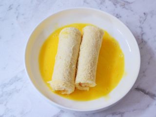 10、芝士火腿吐司卷,把吐司卷放入鸡蛋液中滚一圈，让吐司卷表面均匀地裹上鸡蛋液