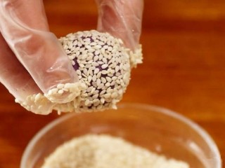 11、紫薯糯米丸子,把搓好的小丸子放入清水中。蘸上一层清水，然后放入芝麻碗中。粘上一层芝麻。