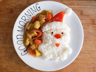 13、圣诞咖喱鸡饭,将煮好的咖喱鸡浇在米饭旁边，在帽子，鼻子和嘴上在涂一层番茄酱增色。