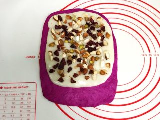 11、火龙果麻薯面包,把擀开的麻薯片铺在面片上，放上切碎的杏仁、开心果和蔓越莓碎，然后轻轻按压下。