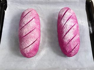 14、火龙果麻薯面包,发至两倍大时取出面包，在表面筛一层薄薄的高筋面粉，用锋利的刀片在面包表面刮出纹理。