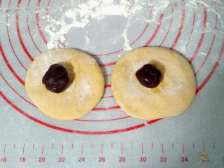 8、宝宝最爱的小蜜蜂豆包,把色的面团分出两个小剂子，一个剂子50克滚圆，按扁，放上豆沙馅儿。