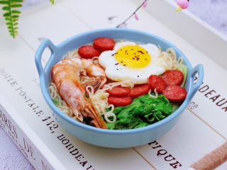 16、对虾红肠时蔬泡面,把煮好的方便面盛到碗里，上面码放好煎过的鸡蛋和红肠，就可以开始享用了。