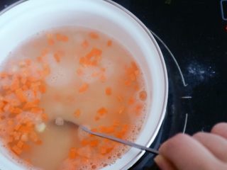 11、宝宝辅食之玉米胡萝卜粥,倒入后需用勺子经常搅拌以免糊锅，这里我们可以用中小火慢慢熬