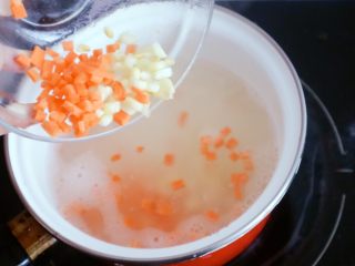 10、宝宝辅食之玉米胡萝卜粥,大火煮一开后倒入切好的胡萝卜丁和玉米粒碎