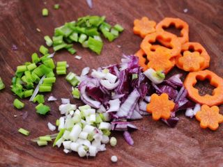 3、核桃仁虾干时蔬蛋炒饭,用刀把胡萝卜刻成小花，青椒切成小丁，洋葱切碎，小香葱切成碎末。