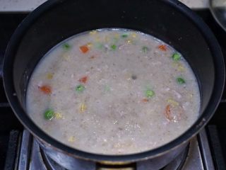 8、瘦肉杂蔬麦麸粥,搅拌均匀后就加入肉丁和杂蔬，再用锅铲搅拌，把肉丁搅散防止黏成一块。