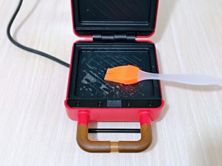 9、快手早餐～香蕉酸奶三明治,三明治机器连接电源，将上下的烤盘刷上少许食用油。