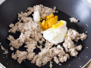 2、咸蛋芝麻葱油酥饼,3. 放入一个煮熟的咸蛋，压碎，炒拌均匀。